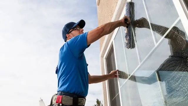 Fensterreiniger zieht eine Glasfläche streifenfrei ab